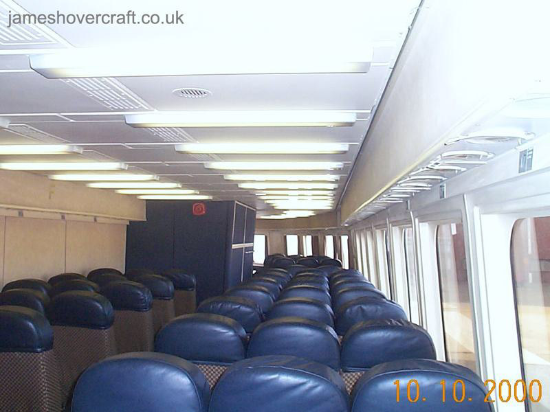 SRN4 systems tour - Looking forward in the starboard passenger cabin. The SRN4 Super-4 was capable of holding 424 passengers and 60 cars in the configuration used by Seaspeed/Hoverspeed. Here is shown the final layout of the cabin before the craft's retirement in 2000. Note the forward galley (blue box like structure), in the approximate position of the front pylon and lift fan assembly, and the pull-down life-jackets for passengers in the overhead compartments. (submitted by James Rowson).